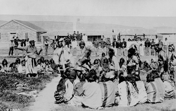 Chief Washakie, arm outstretched on left, with Shoshone dancers, U.S. troops and civilians at Fort Washakie, 1892. National Archives.