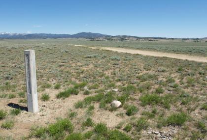 A nearly indistinct segment of Lander Trail next to the concrete marker near a county road west of South Pass, Wind River Mountains on the horizon. Will Bagley photo.