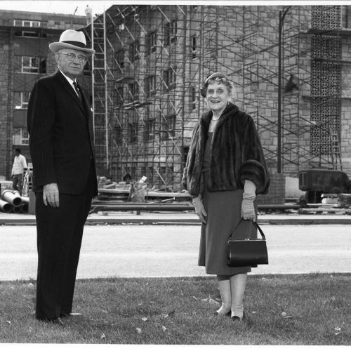 A man and a woman pose in front of a construction site