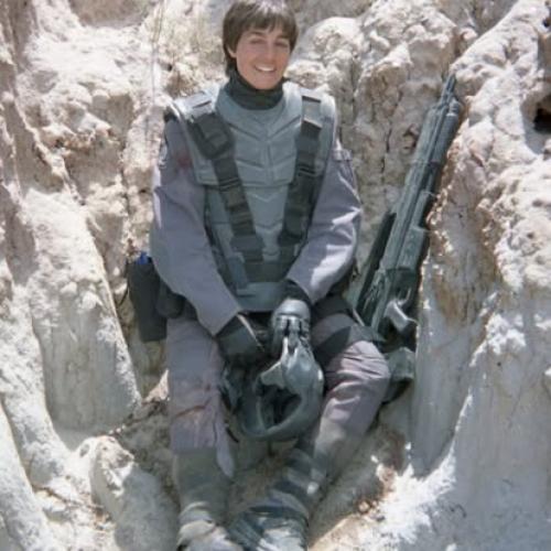 young woman posing in a heavy military costume holding a large gun