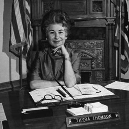 Thyra Thomson at her desk, smiling