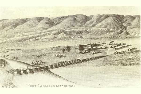 distant view of wooden bridge across a river, leading to an area of sparse low buildings with rounded hills in the distance