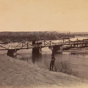 Bridge across the Laramie River near its junction with North Platte River, 1868. The standing man may be Alexander Gardner. William T. Sherman collection of Alexander Gardner photographs; National Museum of the American Indian (NMAI) Archive Center, Smithsonian Institution.