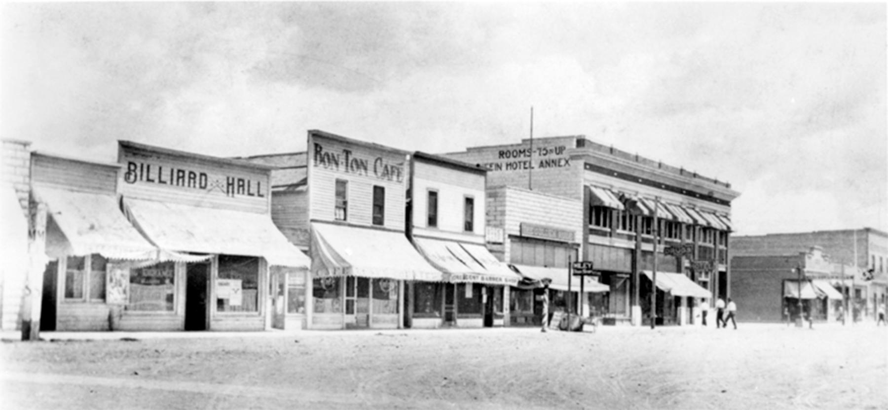 Downtown Greybull, Wyo., about 1918. The black sign with white letters beyond the barber pole and next to the lamppost, center, was for Lizabeth Wiley’s bookstore. Just four feet wide in its first version, the store was wedged between the barber shop and the next building beyond it, the Golden Rule Store (now the Greybull Standard). Wyoming State Archives.