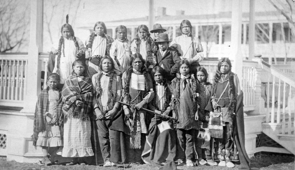 Northern Arapaho and Eastern Shoshone students at the Carlisle Indian School, 1881, shortly after their arrival from Wyoming Territory. Soon, the boys’ braids would have been cut and they would no longer have been allowed to wear traditional dress. The two boys in hats are reportedly Shoshone. John Choate photograph. Click to enlarge