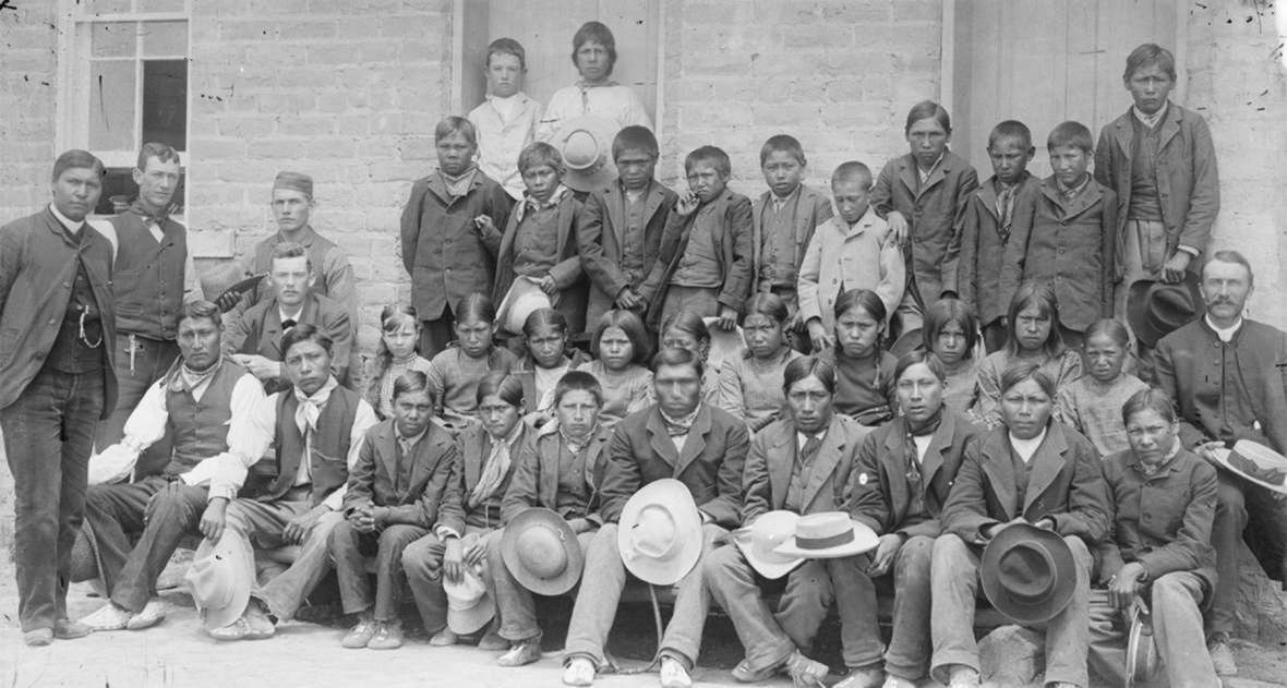 Sherman Coolidge, far left, and Dr. John Roberts, far right, with students and staff at the Episcopal mission school at Fort Washakie on the Eastern Shoshone Reservation, 1880s. American Heritage Center.