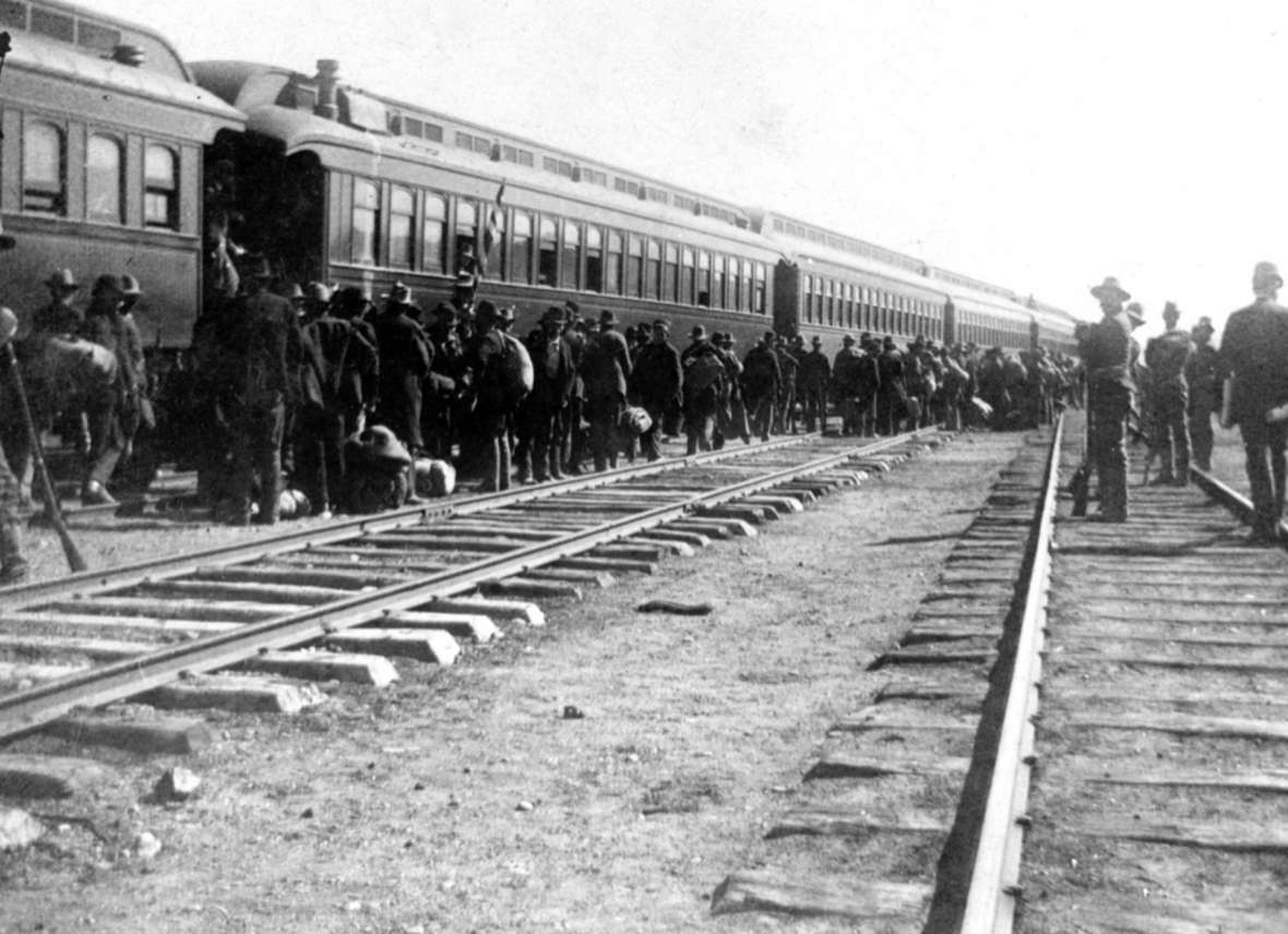 Coxeyites, with federal troops standing guard, board a train in Green River to head back to Idaho, where they were all found guilty and given minor sentences. Sweetwater County Historical Museum.