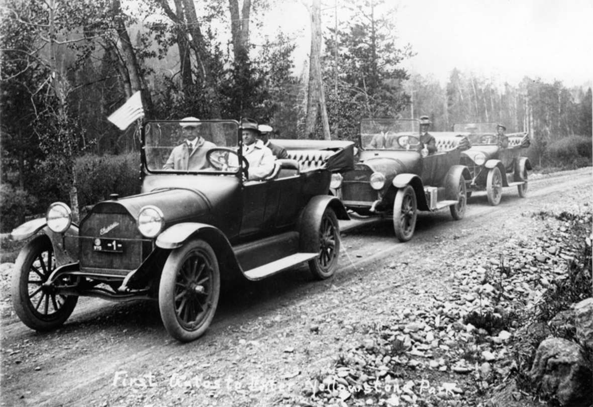Good Roads Movement promoters Jake Schwoob and Gus Holm, in the front car here, were in the caravan of the first cars to enter Yellowstone, 1915. Growth in auto travel to national parks was one of the main drivers behind the naming of national highways in the 1910s and ‘20s, when most of them were still dirt. Park County Archives.