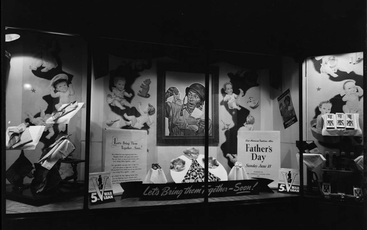 A Father’s Day window display at Woodford’s clothing store in downtown Laramie, 1944, shows a delighted GI holding up a baby bootie that’s just arrived in a letter from home—and features a poem titled, ‘Let’s Bring Them Home—Soon!’ American Heritage Center, University of Wyoming.
