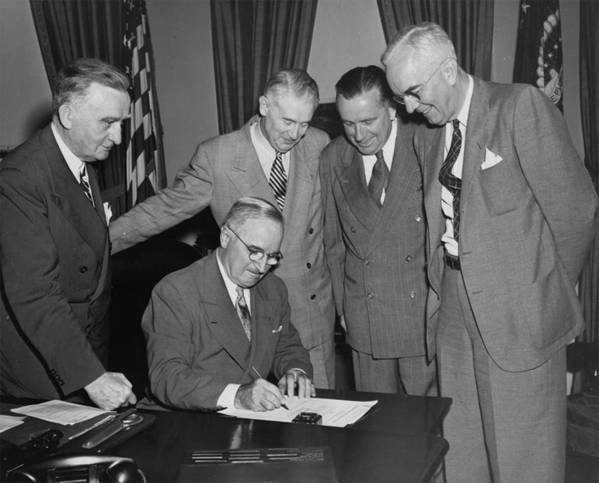 President Harry Truman signs a bill as Wyoming’s two U.S. senators, Joseph O’Mahoney, left, and Hunt, second from left, look on. The other two men are unidentified. Wyoming State Archives.