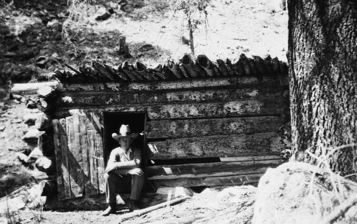 So called 'tuskers,' who poached elk for their valuable teeth, built remote shacks and cabins on public lands in Jackson Hole. Here, Game Warden Charlie Peterson sits in the doorway of a tusker’s cabin, about 1920. Jackson Hole Historical Society and Museum.