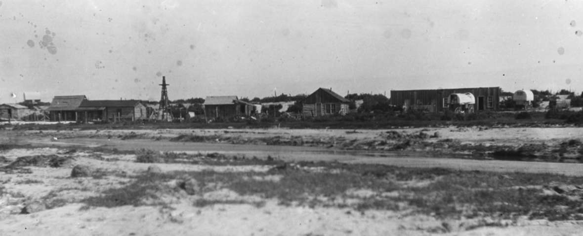 Headquarters of the Love Ranch, 1920s. The smaller of the two reservoirs lies in the foreground. The ice house is at far left. The honeymoon sheep wagon is behind it on the horizon; the main ranch house with its porch is next to the right. The log building with the peaked roof is the bunkhouse. Love family photo.