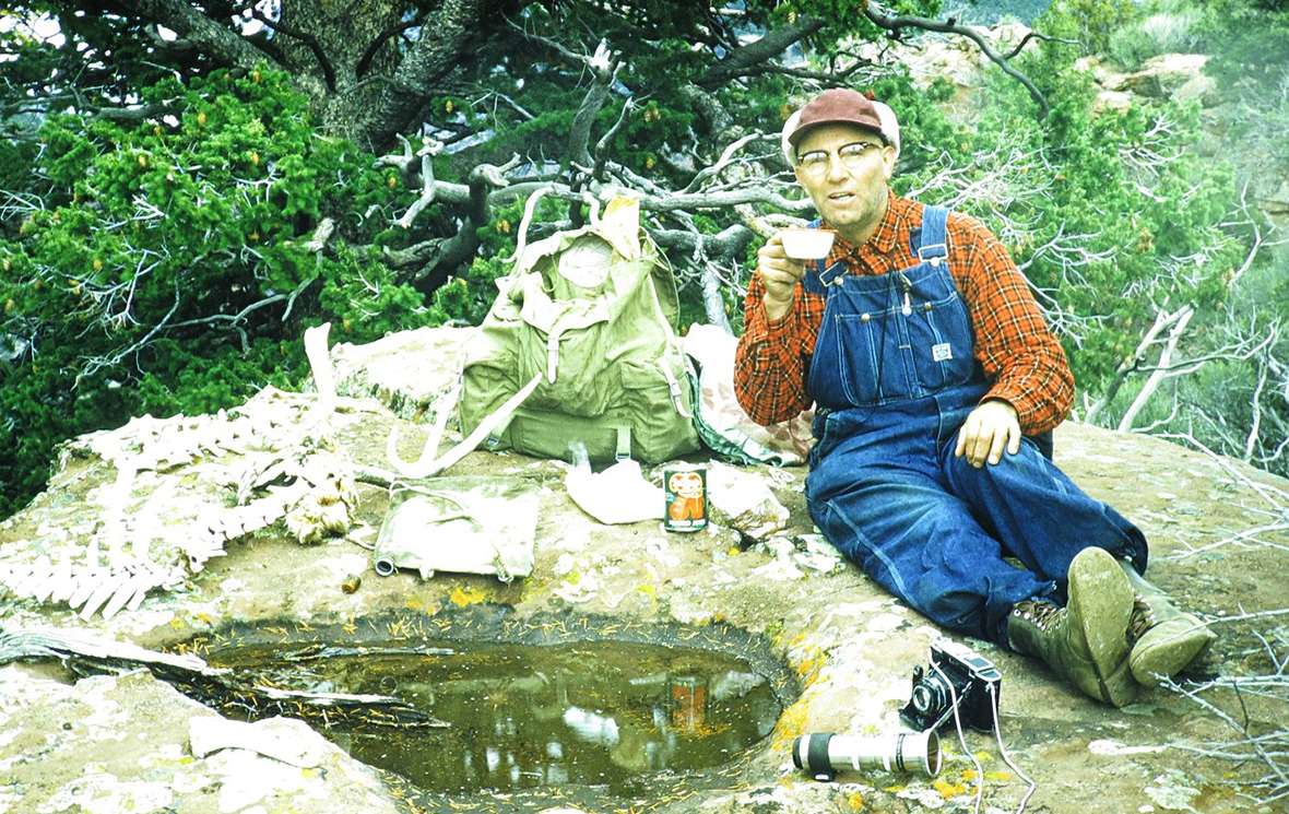 Finis Mitchell with his canvas water bag, camera, long lens and can of tomato juice on a hiking trip to Lodore Canyon of the Green River in Utah, 1954 or '55. Mitchell spent as much time as he could in the mountains. American Heritage Center. 