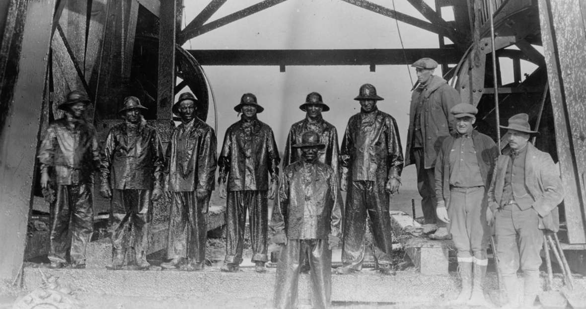 Roughnecks after capping a gusher in the Salt Creek Field, 1920s. The men on the right, who are not wearing slickers drenched in oil, are probably investors in the well. American Heritage Center, University of Wyoming. 