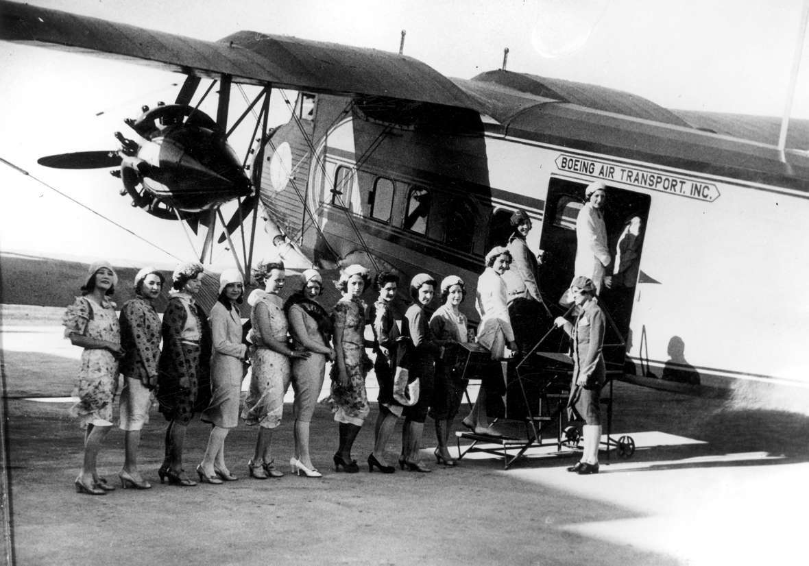 On a windy day in 1930s Cheyenne, newly recruited Boeing Air Transport stewardesses (all of them unidentified) line up to board a flight on a Boeing Model 80A aircraft. Wyoming State Archives.
