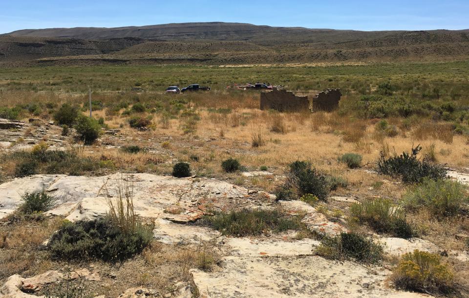 open grassy plain with a few ruined building walls standing in the distance