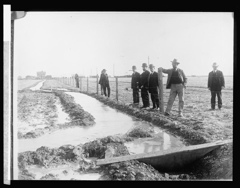 Several man stand near an irrigation ditch