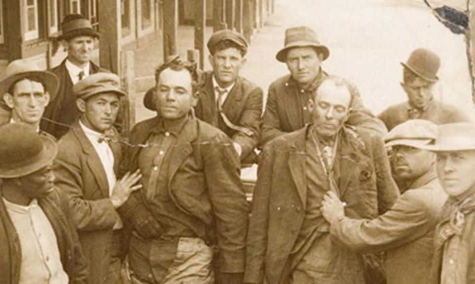 a group of men hold the bodies of Ben Kilpatrick and Ole Hobek upright