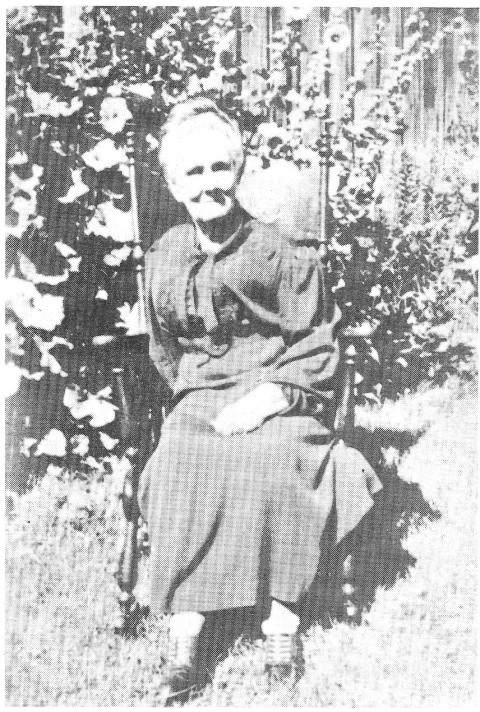 Photo of elderly woman seated in a chair outside.