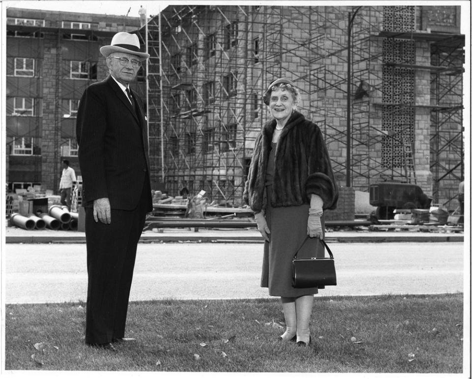 A man and a woman pose in front of a construction site