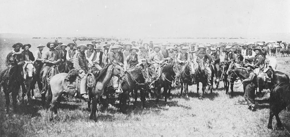 large group of mounted cowboys posing on an open plain