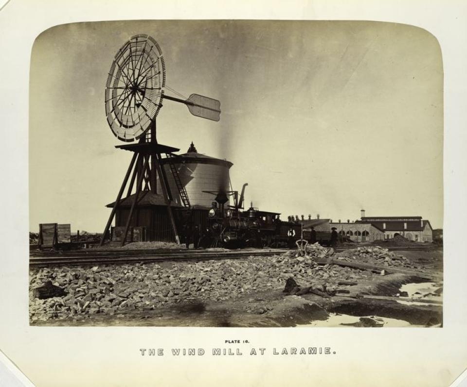 windmill and water tank next to railroad tracks