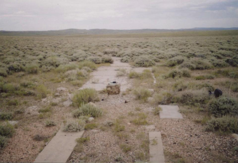 The powerhouse foundation and part of the concrete directional arrow from the field at Dana, Wyo., show through the sagebrush, 2009. Author photo.