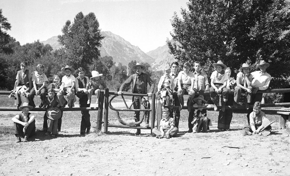 Larry Larom and dudes at a gate on the Valley Ranch southwest of Cody, 1930s. Note the "VR" configured into the gate, along with the ranch's brand, which shows also on the front of Larom's boots in the previous photo. Charles Belden photo, American Heritage Center.