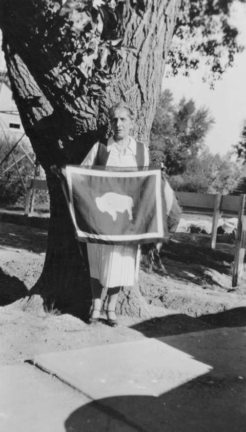 Suffragist, University of Wyoming professor and former Wyoming regent of the D.A.R. Grace Raymond Hebard holds up a state flag in July 1930. The bison in this version faces the viewer’s left—implying that it would fly facing the flagpole—as Hebard demanded. American Heritage Center.