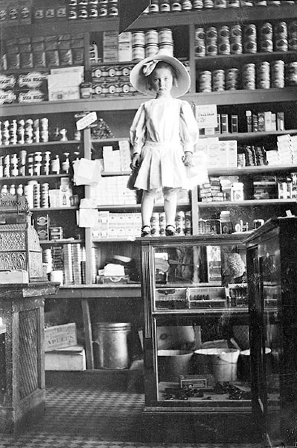 Ruth Parr stands on a store counter in Encampment, 1912. Lora Nichols Collection, Grand Encampment Museum.