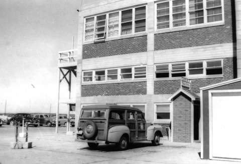 This 1951 photo shows the three-story building that housed the United Air Lines stewardess training facility at Cheyenne and a station wagon used to transport the students. Courtesy of Patricia Seibel Romeo.