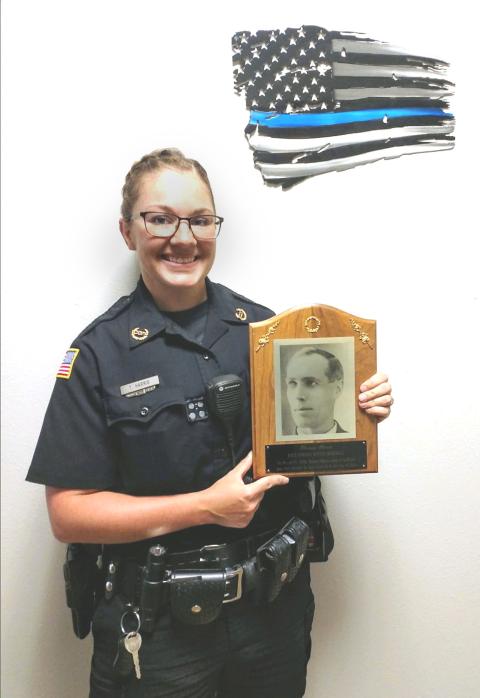 woman polic officer in uniform hold up and plaques with a photo of her ancestor Harris