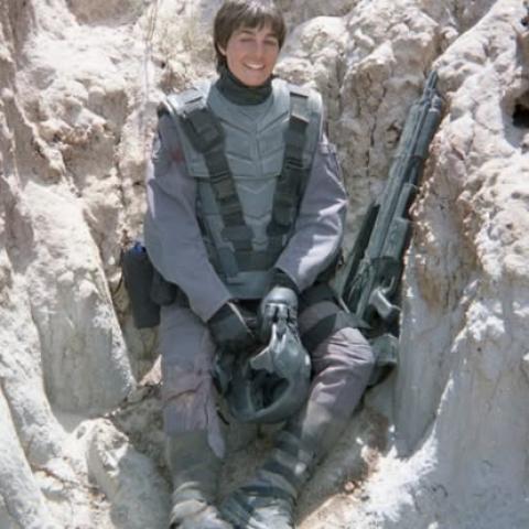 young woman posing in a heavy military costume holding a large gun