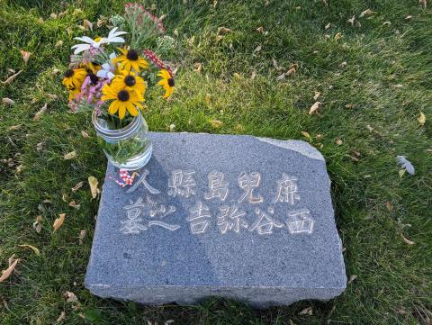 granite headstone with jar of flowers, engraved with Japanese letters