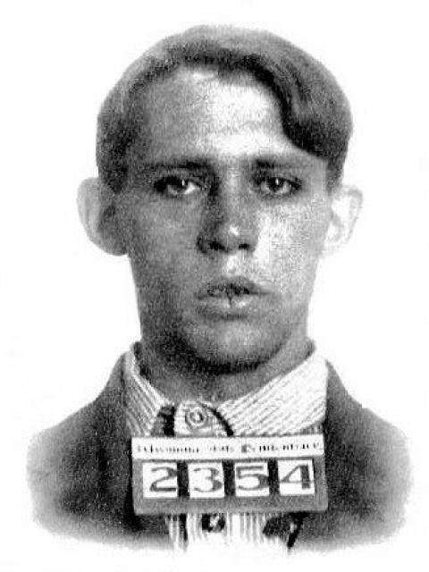 Mugshot of a young man with a sign showing the numbers 2354 on his collar