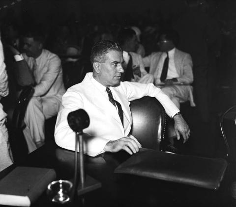 Dr. Rexford Tugwell seated informally at a table with a microphone