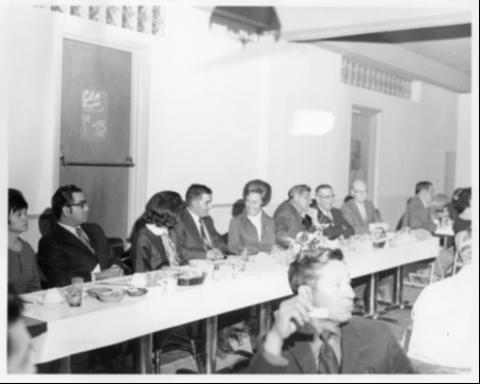A banquet table with many people seated, talking to one another