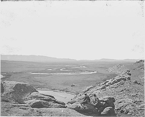 View from a rocky rise overlooking vast treeless plain with a curving river in the distance
