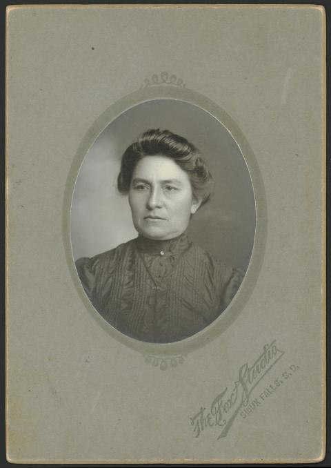 portrait of a woman in a high-necked dress with her hair arranged on the top of her head